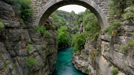 ancient bridge over a turquoise river canyon