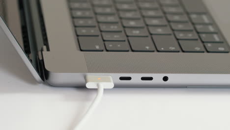 close up, person plugging in magsafe charger to new m1 macbook pro