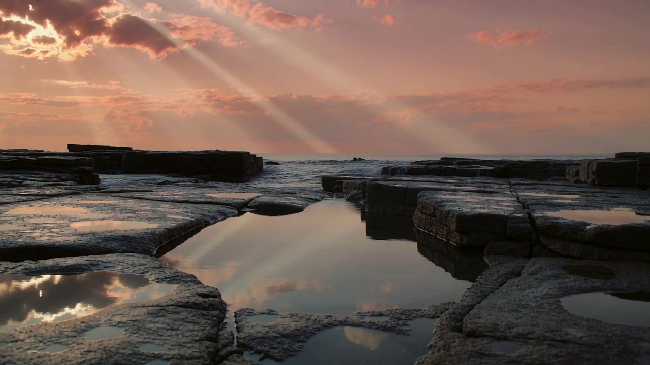 Capturing tidal shelf with small pools mirroring dusk rays, wave nearing ledge and spilling over