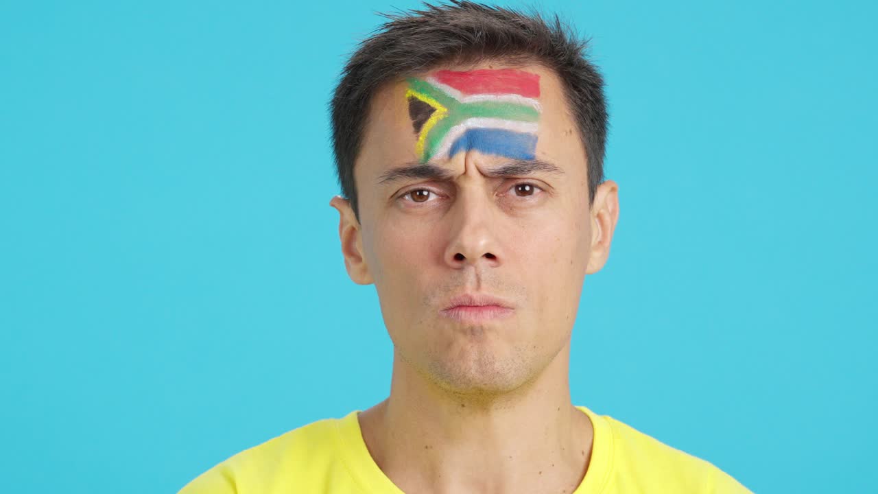 Serious man with a south african flag painted on the face