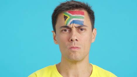 serious man with a south african flag painted on the face