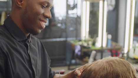 positive afro-american barber cutting hair of client