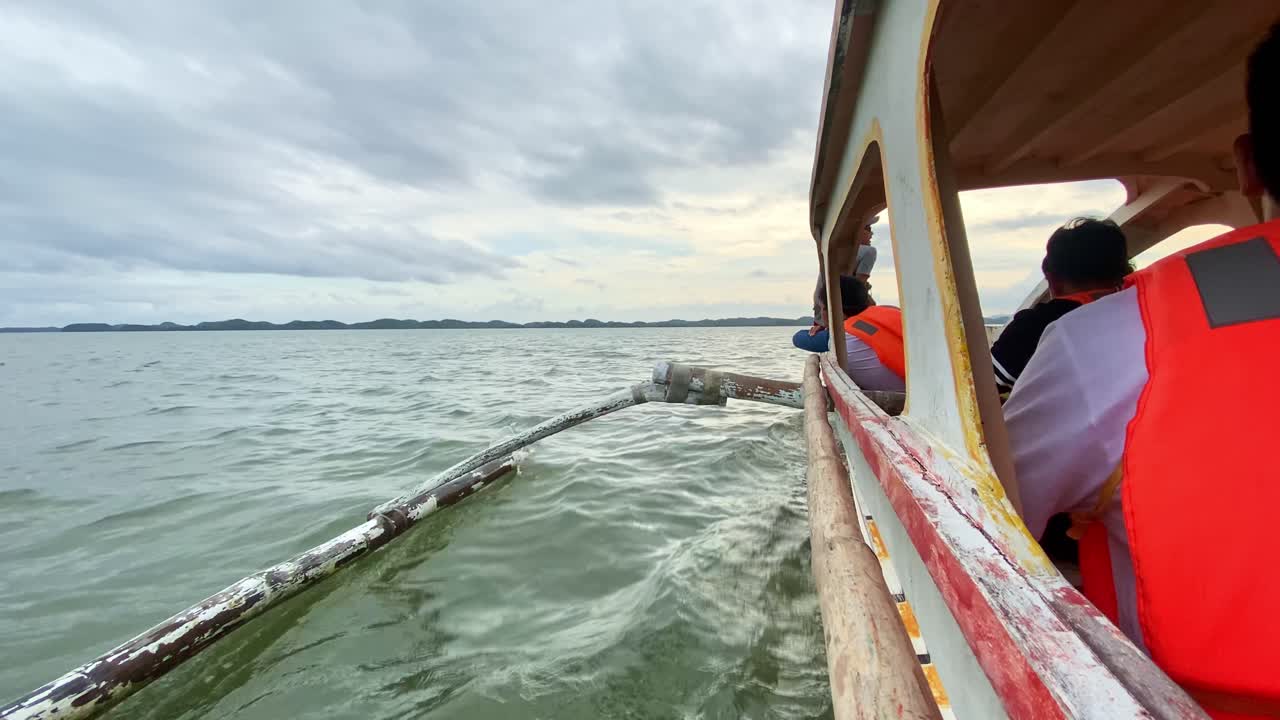 Wide Angle of Bangka Boat Carrying Tourists Sailing through Grey Tropical Waters - Tourist Travel and Destination