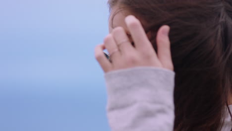 portrait of beautiful caucasian woman wearing sunglasses enjoying peaceful seaside at sunset looking contemplative running hand through hair