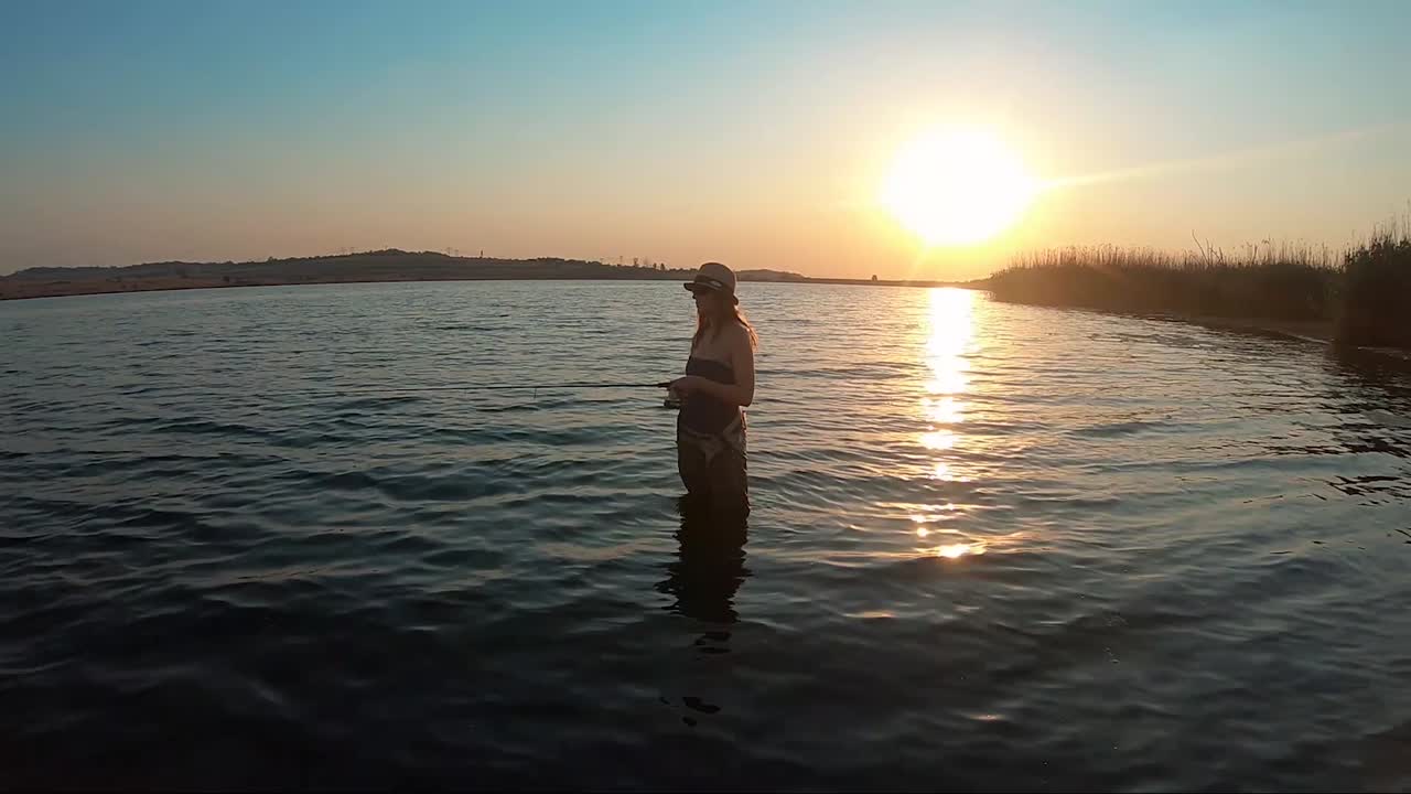남아프리카 공화국의 배경에서 아름다운 일몰과 함께 호수에서 아름다운 소녀 배스 낚시의 전망