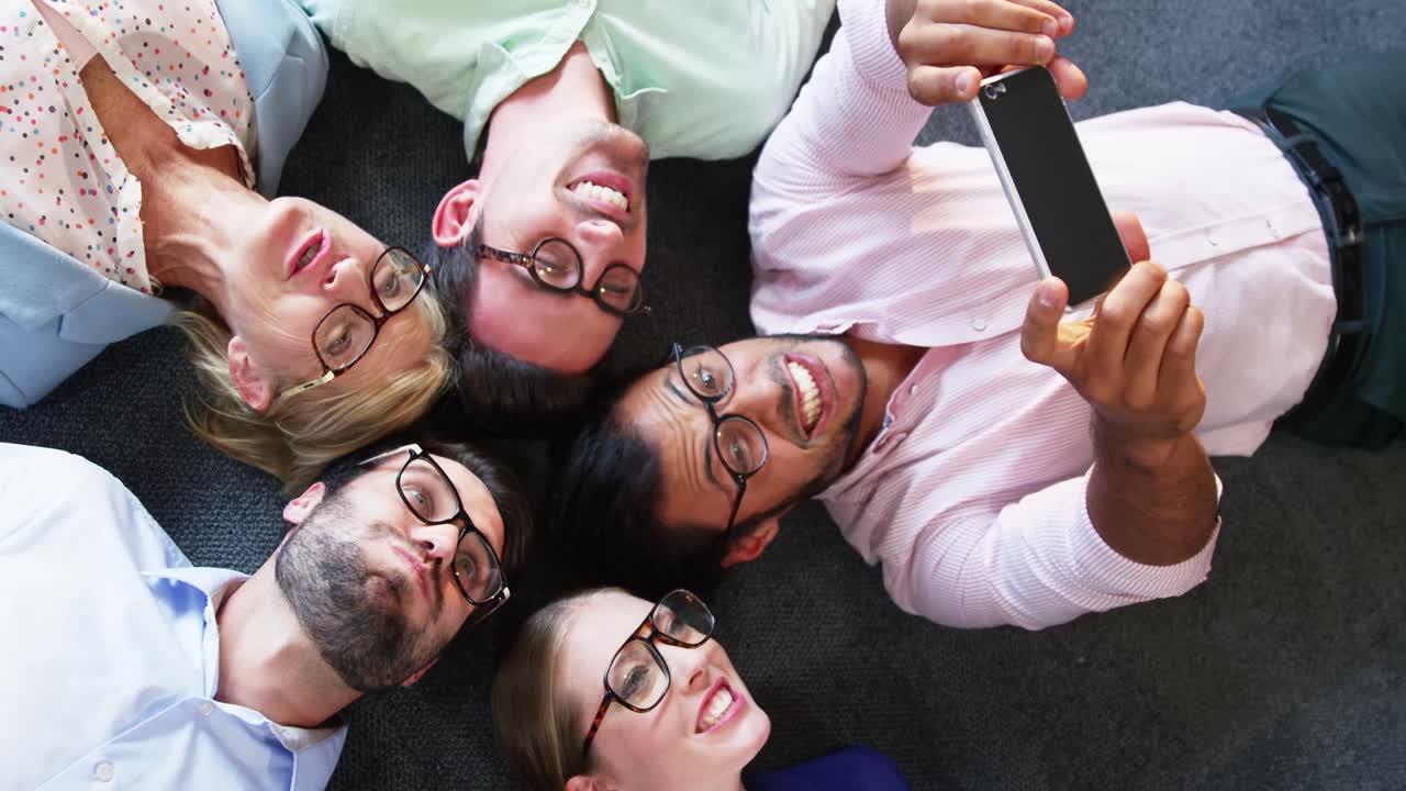 ejecutivo de negocios tomando una selfie desde el teléfono móvil mientras está acostado en el suelo
