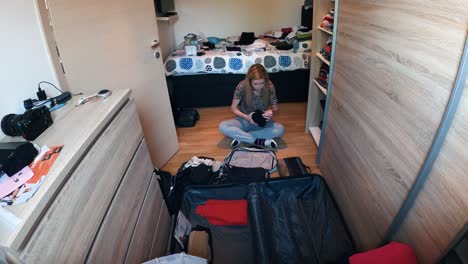 a young lady is packing her bag and suitcase, ready to travel