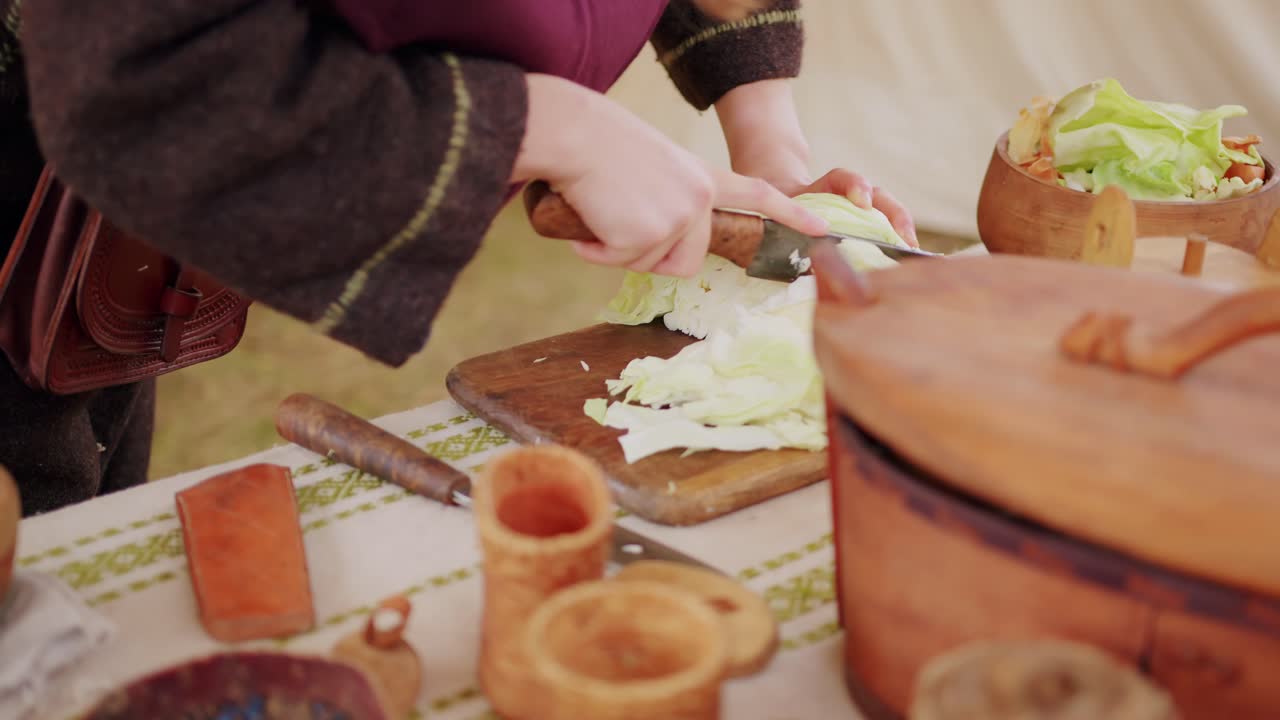 수세기 전처럼 역사적인 요리를 준비하기 위해 양배추를 자르는 중세 의상을 입은 여성
