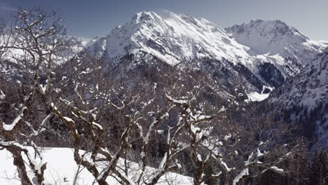 Toma-Aérea-De-Un-Hermoso-Paisaje-Invernal-Con-Montañas,-Nieve-Y-Sol