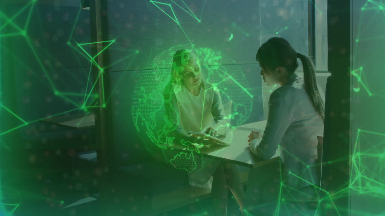 Two women discussing at table with digital globe and network animation overlay