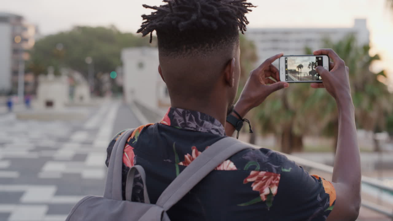 portrait young african american man using smartphone taking photos enjoying photographing vacation destination on mobile phone camera technology slow motion