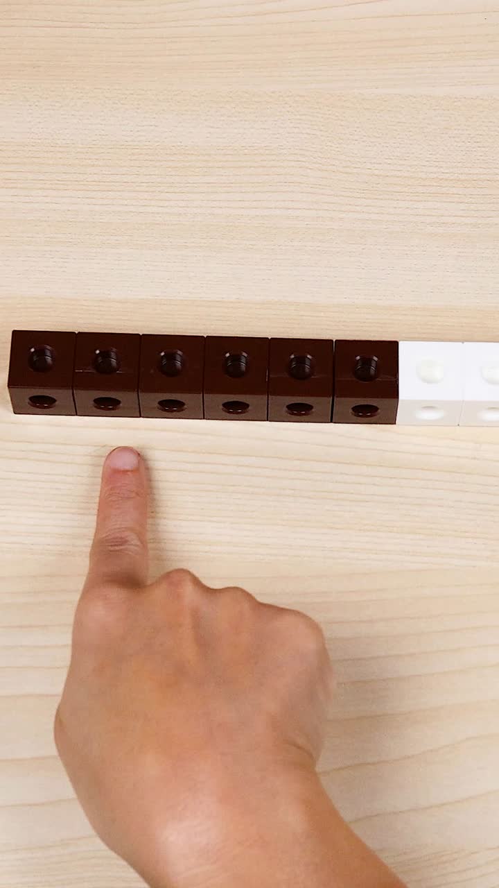 손은 테이블 위에 있는 다채로운 연결 큐브를 조작합니다.