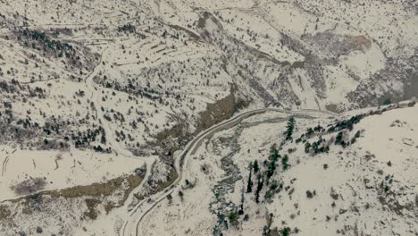 Imágenes-Cinematográficas-De-Drones-Inclinados-De-Montañas-Cubiertas-De-Nieve-Con-El-Valle-Del-Norte-De-Pakistán,-Valle-De-Naltar,-Gilgit