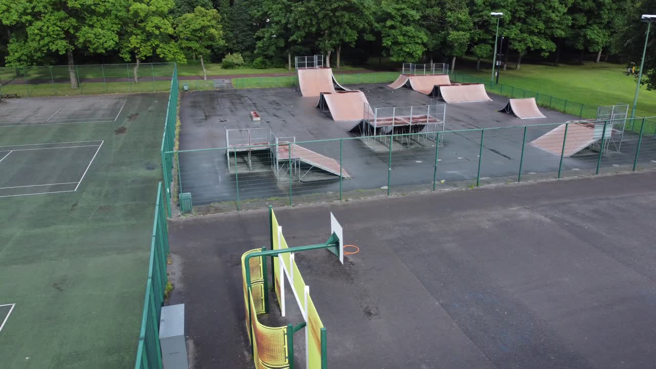вид с воздуха, пролетающий над огороженным скейт-парком, баскетбольным и теннисным кортом на пустой закрытой игровой площадке
