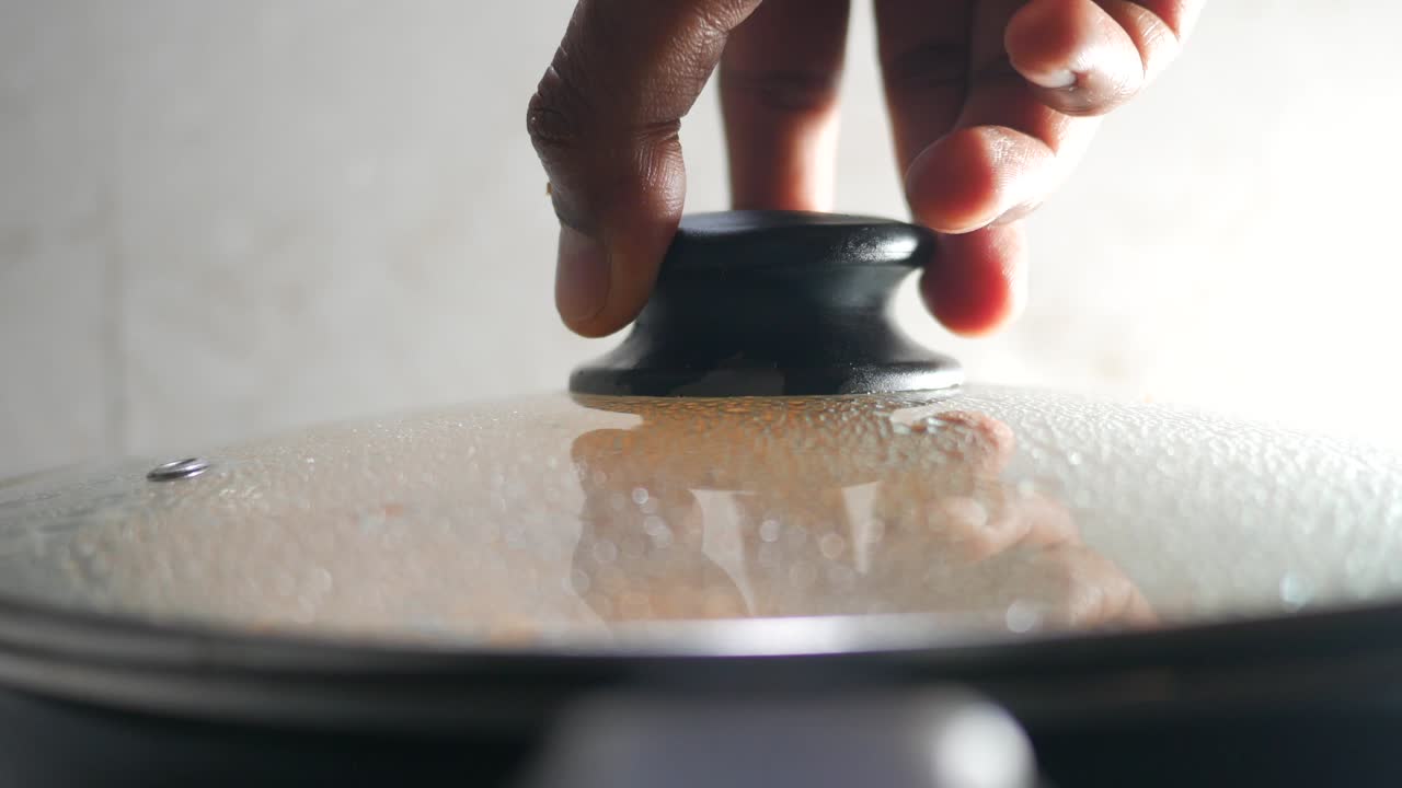 Cooking Process: Hand Lifting Lid from Steaming Pan
