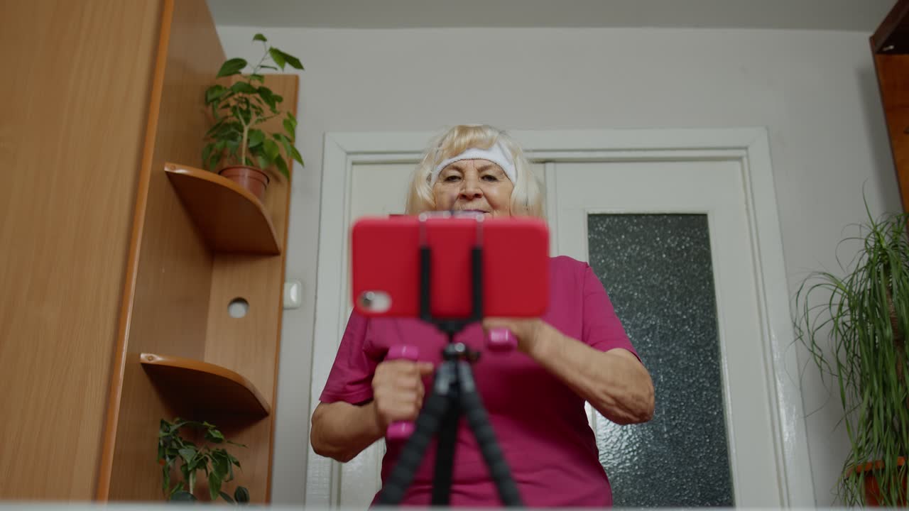 Anziana nonna che si allena con i manubri, corre, fa fitness e attività sportiva a casa.