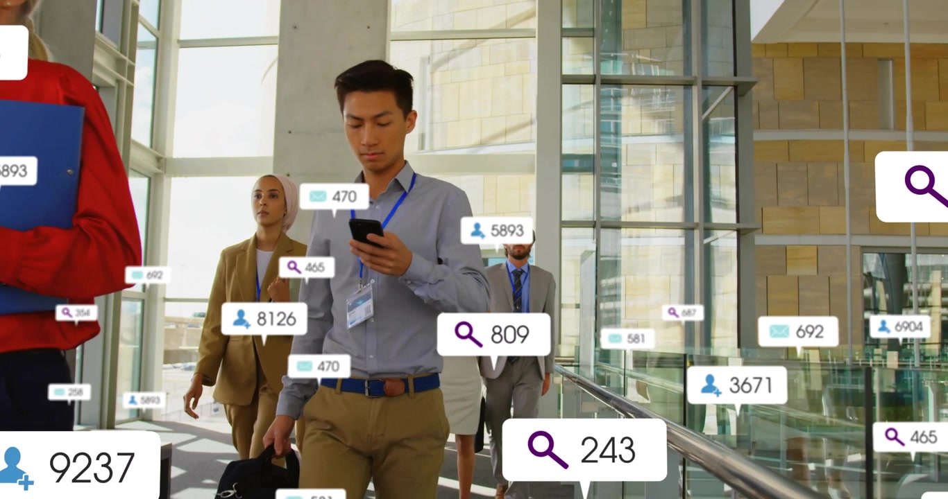 Sekelompok orang berjalan di atrium kaca, seorang pria memeriksa ponselnya dengan overlay data yang berkembang menampilkan pesan bisnis.