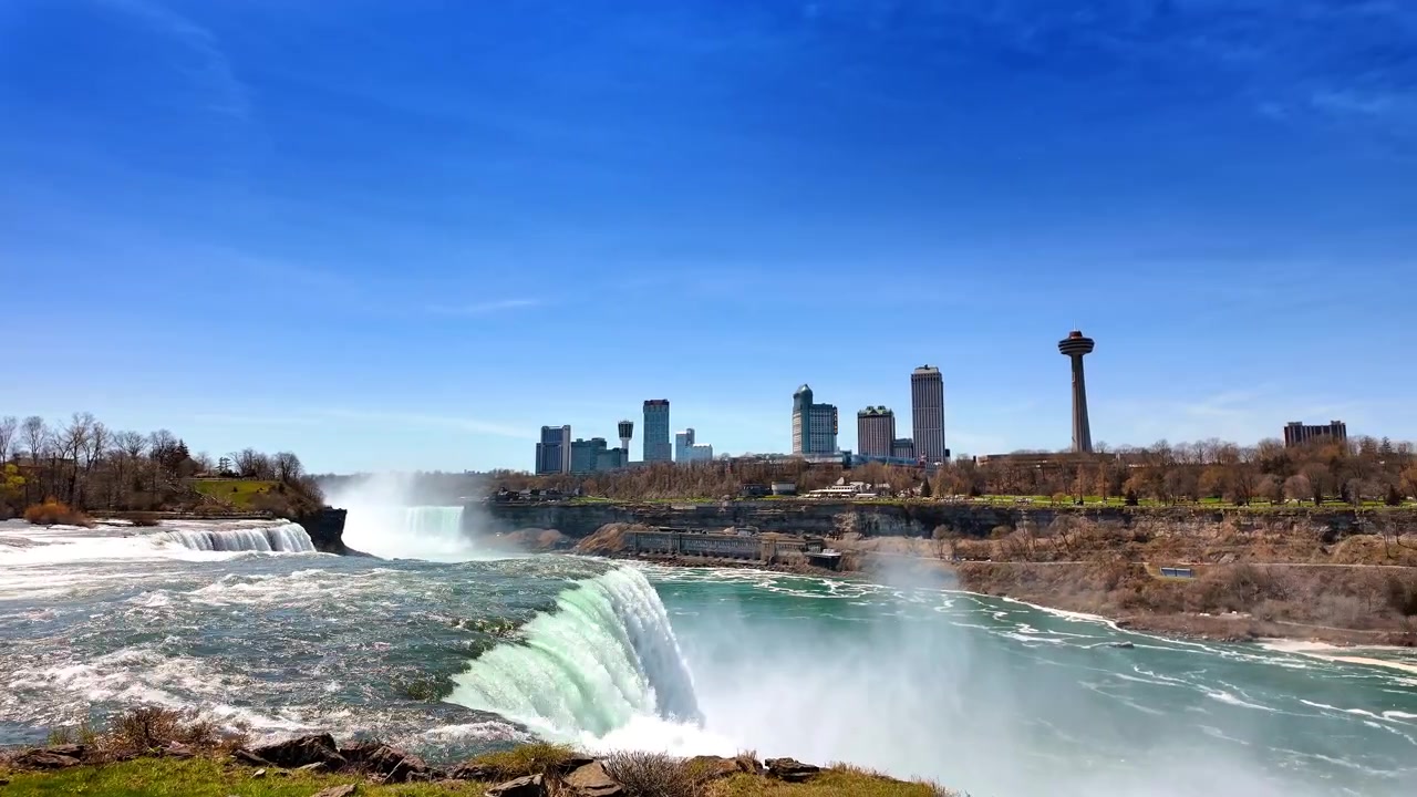 Ontario, Canadá, 9 de agosto de 2025: Cataratas del Niágara durante un día despejado con el horizonte de la ciudad de fondo y agua cayendo por las rocas