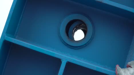 close-up of a blue metal component with a circular hole and bearing