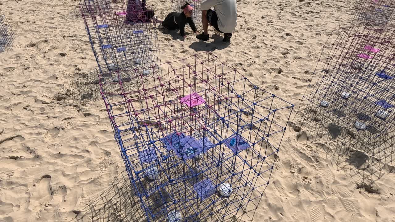 personas que se involucran con la instalación de esculturas de playa