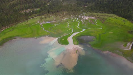 Aerial-shot-of-great-Lake-Dobbiaco-and-green-grass-in-Toblacher-See,-South-Tyrol,-Italy