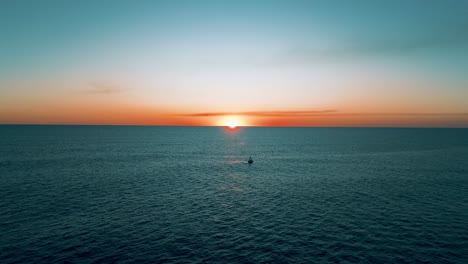 Hermosa-Puesta-De-Sol-Con-Tonos-Cálidos,-Toma-Aérea-Con-Un-Dron-Volando-Sobre-El-Océano-Pacífico-Y-La-Playa-En-El-Salvador-Con-Un-Barco-En-Primer-Plano