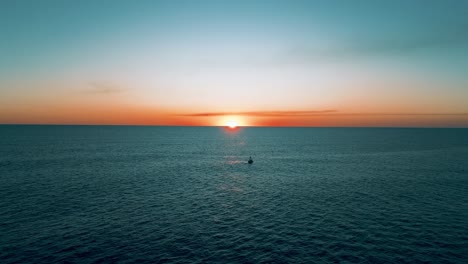 hermosa puesta de sol con tonos cálidos, toma aérea con un dron volando sobre el océano pacífico y la playa de el salvador con un barco en primer plano