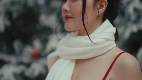woman wearing a white scarf in front of a christmas tree