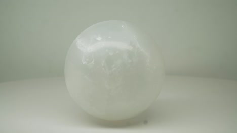 white crystal round l magic ball rotating clockwise with pure white background -close up shot