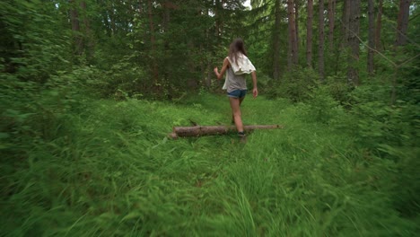 first person view with camera shake walking through the woods tilting down from the tree tops to follow behind a tall brunette woman on a hike