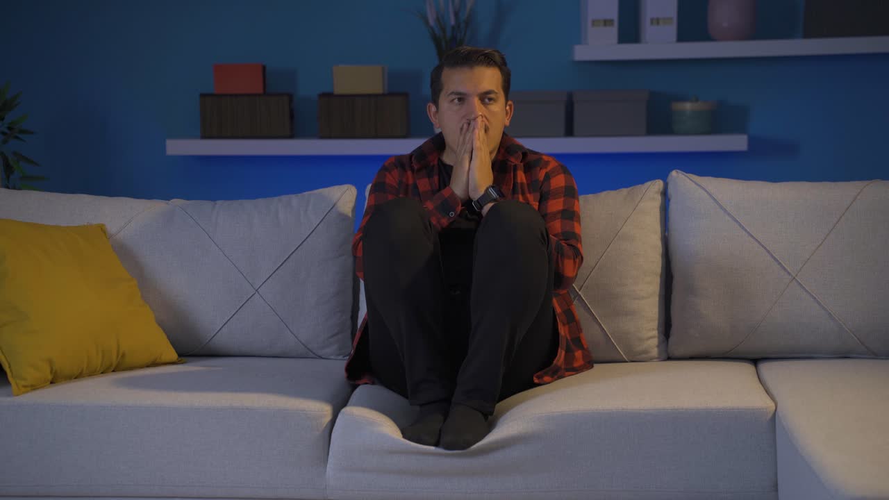 un hombre deprimido cubriéndose la cara con la mano.