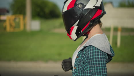 close-up of a female biker adjusting her clothing while wearing a red-and-black helmet and black protective gloves