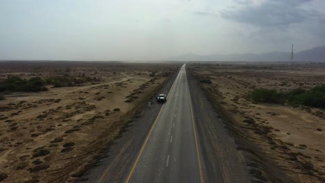 aerial over along road through desert plains in balochistan with truck parked on side