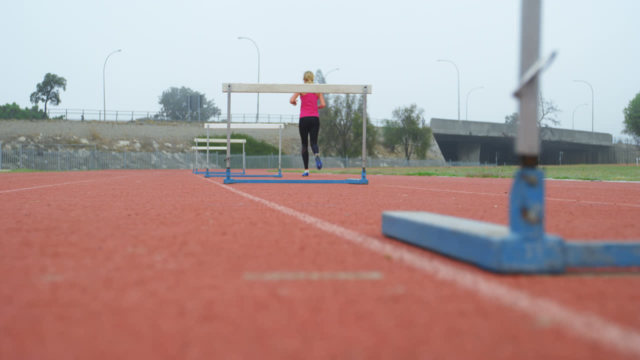 vista trasera de una atleta corriendo en una pista de atletismo en un lugar deportivo 4k