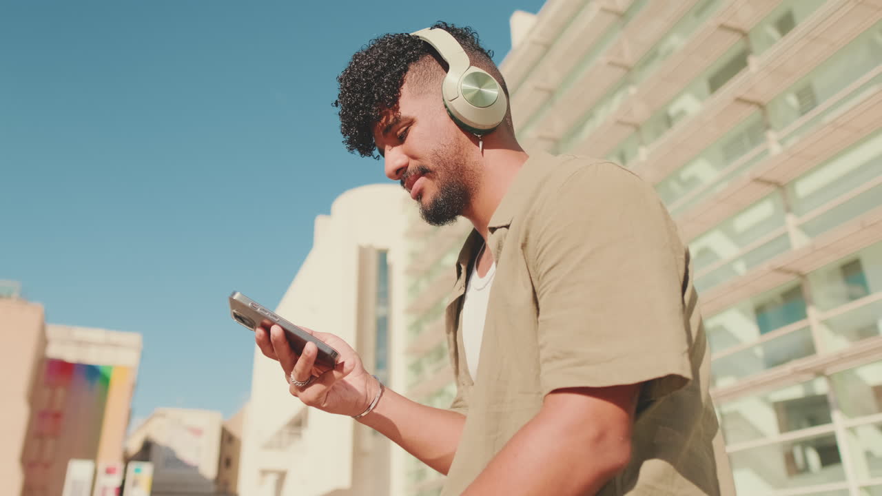 Uomo con le cuffie che usa il cellulare all'aperto