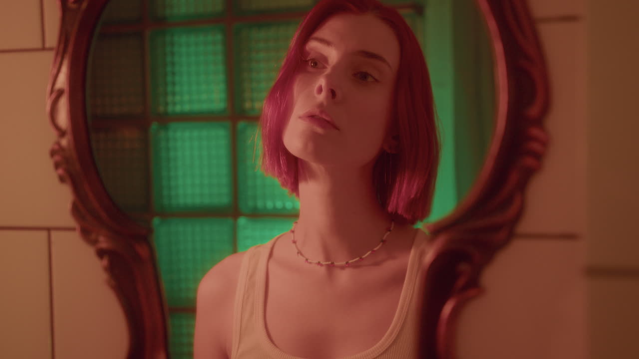 chica bonita mirando su reflejo en el espejo vintage en el baño