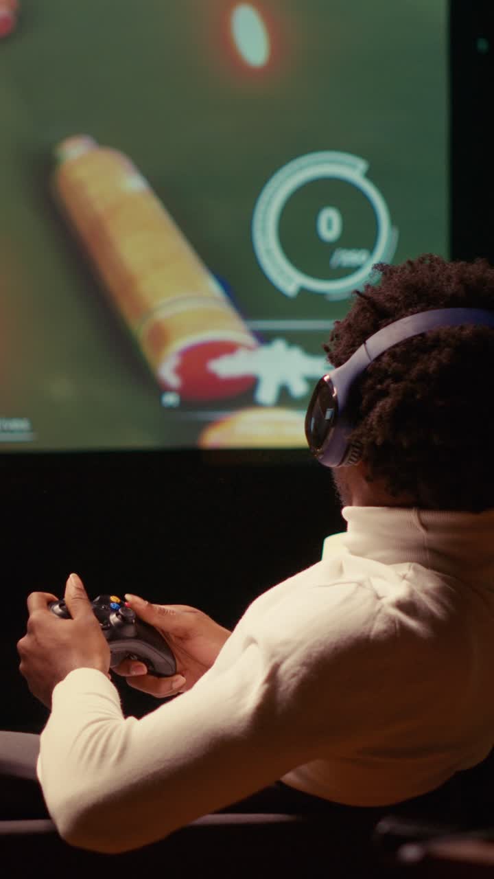 Video verticale di un uomo che gioca a un videogioco per giocatore singolo su una smart TV ultrawide, mentre indossa le cuffie per sentirsi immerso.