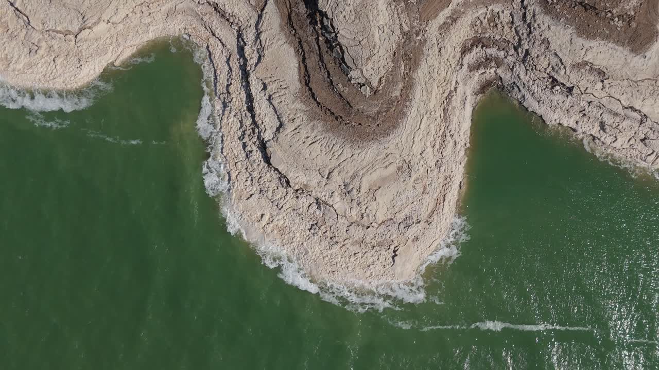 A striking high-angle aerial perspective of the unique white salt crystals and turquoise mineral waters along the shores of the Dead Sea, Jordan