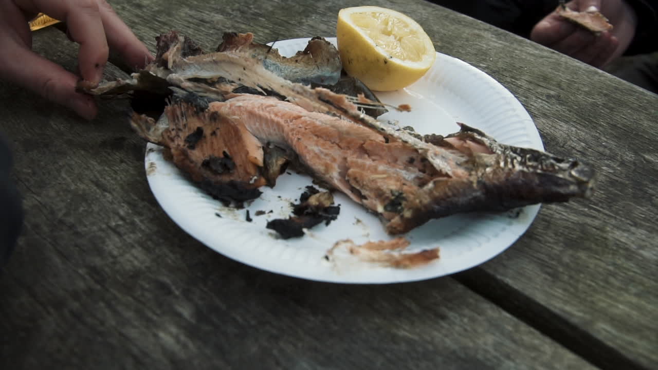 pescado a la parrilla al aire libre comiendo con las manos