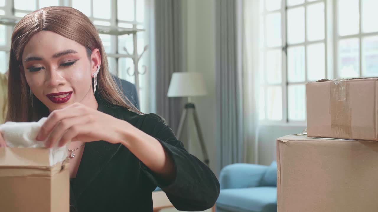 Young Asian Transgender Woman Business Owner With Boxes On The Table Happy Online Sales Job, Get An Order From Customers, Packing Box Delivery Products To Customers