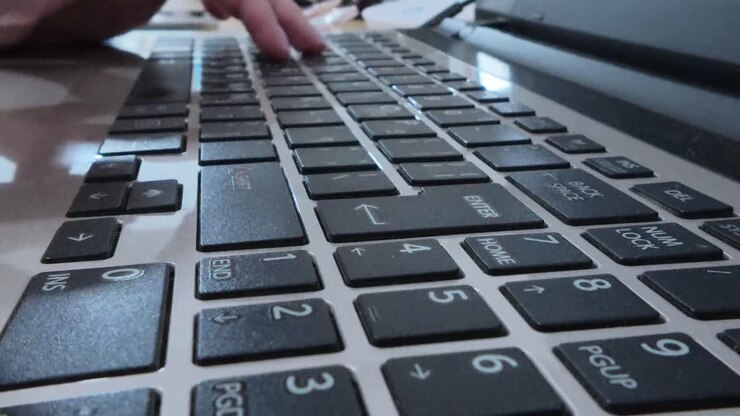 Side view of freelancer woman's hands typing on a laptop, essential for independent work.