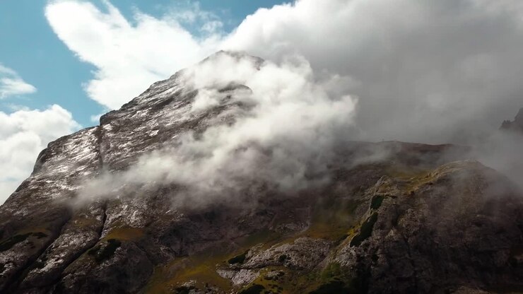 Vetta dolomitica nel Nord Italia con l'umidità che forma una nuvola durante la stagione invernale, ripresa aerea con carrellata all'indietro che rivela la scena