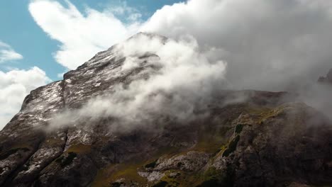 Dolomite-mountain-peak-in-northern-Italy-with-moisture-forming-a-cloud-during-the-winter-season,-Aerial-dolly-out-reveal-Shot