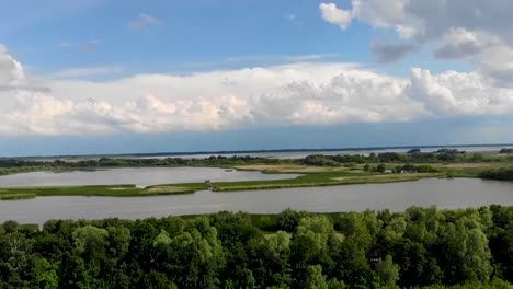 Ascending-drone-shot-over-a-swampy-terrain-with-fluffy-white-clouds