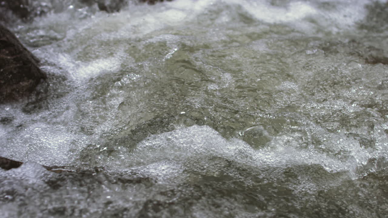 Close up slow motion pan across fast moving water in a rapids in Suck Creek in Chattanooga, Tennessee.