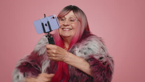 senior woman blogger taking selfie on smartphone selfie stick, dancing, communicating video call