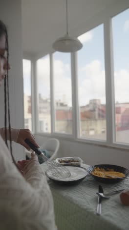 woman cooking breakfast at home by the window