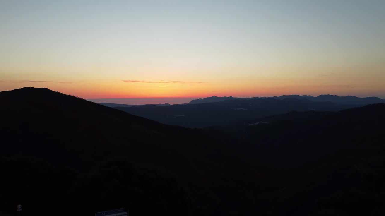 un avión no tripulado vuela sobre montañas y árboles con silueta