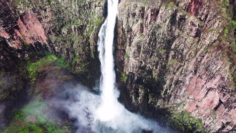 drone flying towards huge waterfall, camera tilts down for amazing perspective