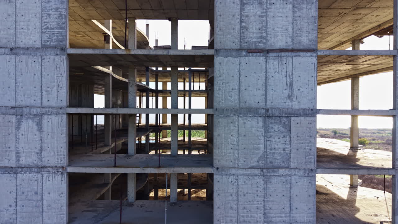 Construction phase reveals the skeletal structure of a building with open spaces under the bright afternoon sun on a clear day